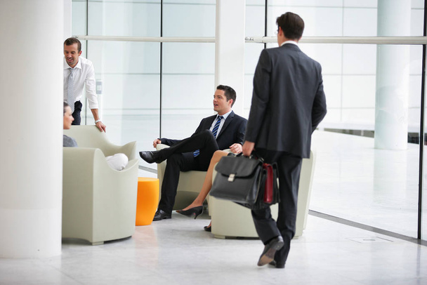 Men in suits and women sitting on a chair talking in a modern society - Foto, Imagen