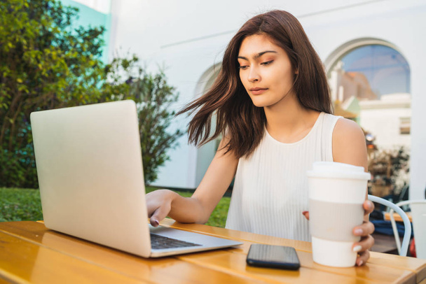 Giovane donna che utilizza il computer portatile alla caffetteria. - Foto, immagini