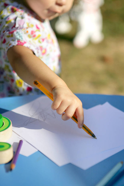 Little girl with a pen in hand making scribbles - Fotó, kép