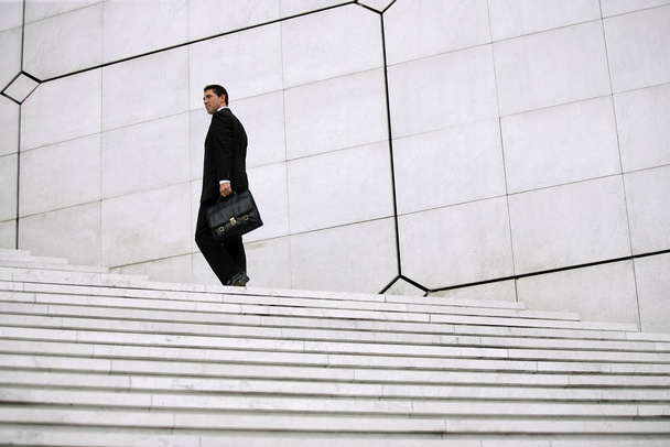 man in suit with briefcase amount of steps before building - Fotó, kép