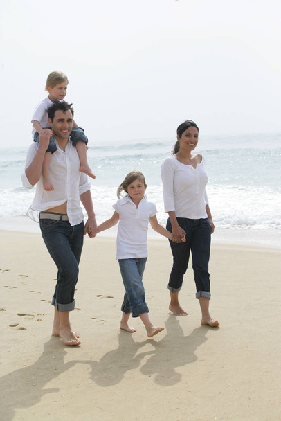 Man and woman with children strolling on the beach - Foto, imagen