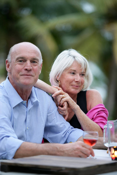 Portrait of an elderly couple sitting at a table on the terrace - Φωτογραφία, εικόνα
