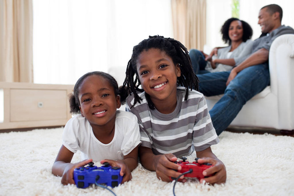 Happy siblings playing video game lying on the floor - Фото, изображение