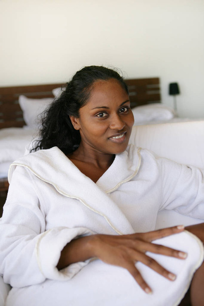 Portrait of a young Mtis woman smiling in a bathrobe in room  - Фото, изображение