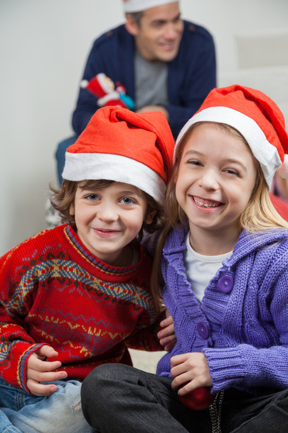 Happy Siblings Wearing Santa Hats At Home - Fotoğraf, Görsel