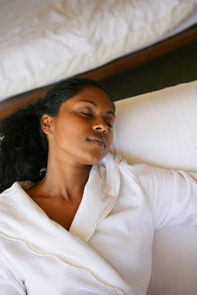 Portrait of a young Mtis woman in bathrobe lying on a bed by turning a blind ey  - Фото, зображення
