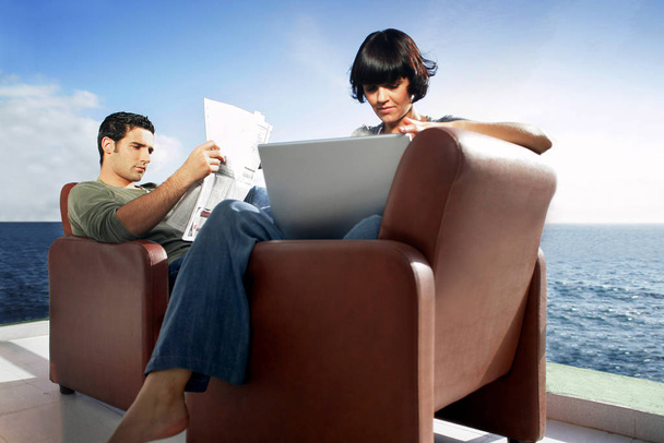 man sitting in an armchair on the terrace reading the newspaper and woman sittin - Фото, зображення