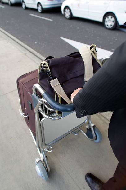 man in suit walking by pushing his luggage trolley profile - Foto, immagini