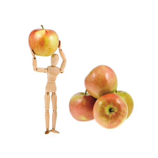 drewniany model trzyma jabłko w pobliżu kupie jabłka - Zdjęcie, obraz