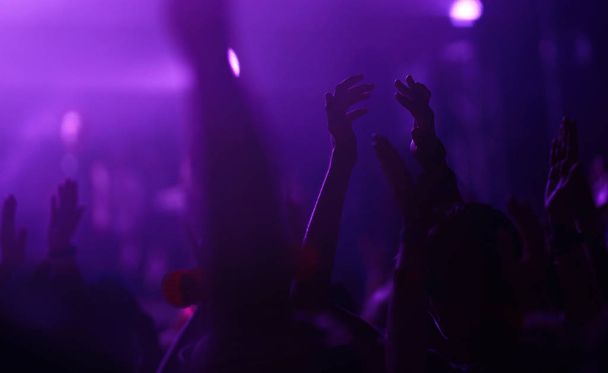 Público con las manos levantadas en un festival de música y luces que fluyen desde arriba del escenario. Multitud levantando las manos, bailando y disfrutando mucho del concierto
. - Foto, imagen