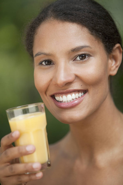 Closeup of young woman drinking orange juice in outdoor setting. Vertically framed shot. - Foto, imagen