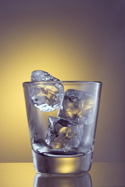 Glass with ice cubes on plain background - Фото, зображення