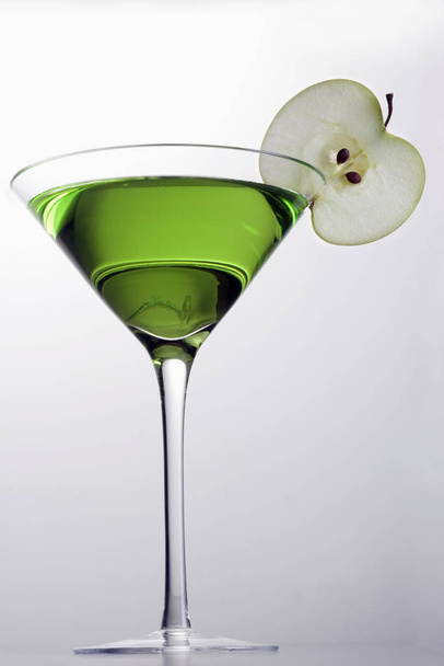 Apple Martini mixed drink with apple slice garnish on grey background - Foto, afbeelding