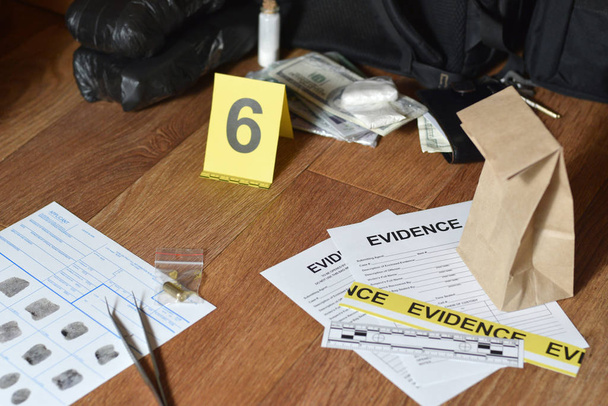 Łańcuch Etykietek Dowodzenia i brązowa papierowa torba z odciskami palców wnioskodawca karty leży przeciwko dużych paczek heroiny i paczek banknotów jako dowód w procesie dochodzenia miejsca zbrodni - Zdjęcie, obraz