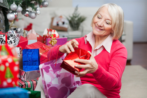 Woman Looking In Bag While Sitting By Christmas Gifts - Zdjęcie, obraz