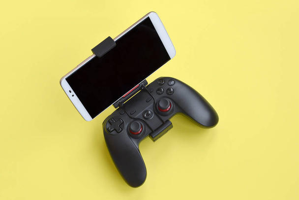 Moderno gamepad nero per smartphone su sfondo giallo. Dispositivo mobile per videogiochi
 - Foto, immagini