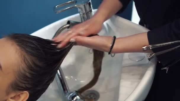 Schönheits-, Haarpflege- und People-Konzept - glückliche junge Frau mit Friseurwaschkopf im Friseursalon - Filmmaterial, Video