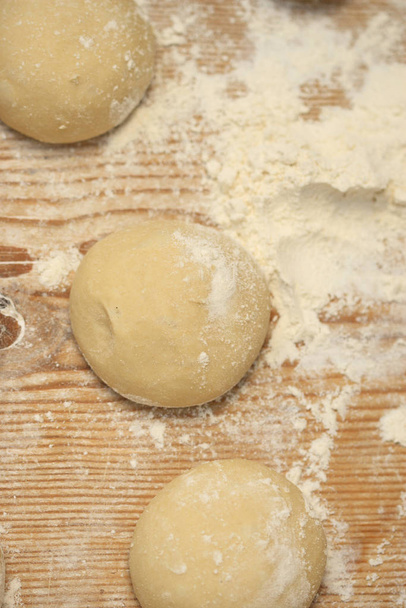 raw dough on wooden table - Foto, afbeelding