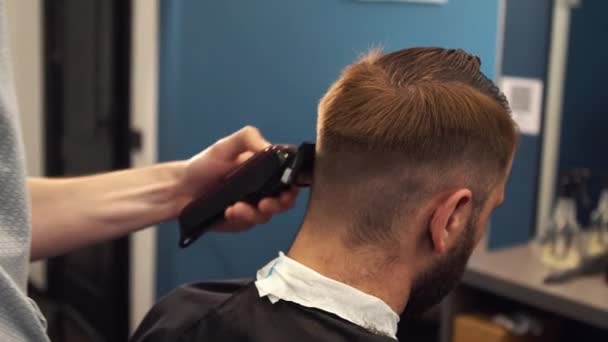 Close up shot of man getting trendy haircut at barber shop. Male hairstylist serving client, making haircut using machine and comb - Metraje, vídeo