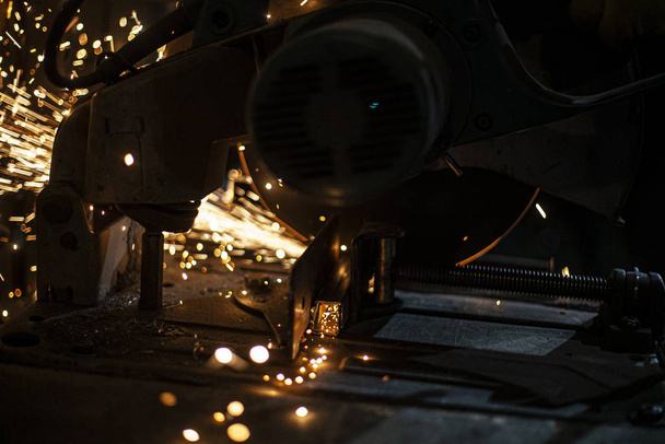 Metal cutting. Grinding steel. Work as a grinder. Sparks from friction. Men's work. Creating a design. The project in the workshop. Iron processing. Hand electric tool. - 写真・画像