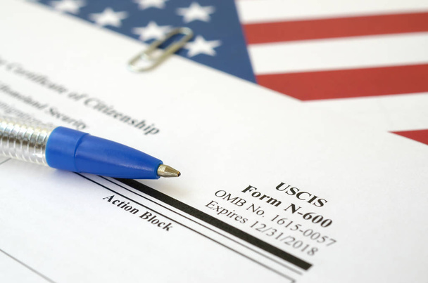 N-600 Aanvraag voor Certificaat van Burgerschap blanco formulier ligt op de vlag van de Verenigde Staten met blauwe pen van het ministerie van Binnenlandse Veiligheid - Foto, afbeelding