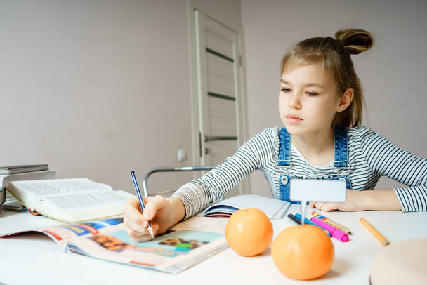 Дівчина-підліток робить домашнє завдання за столом вдома, готуючись до шкільного тесту
 - Фото, зображення