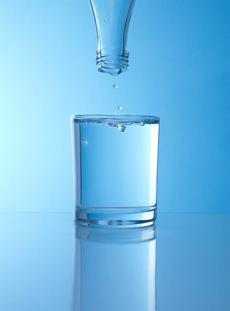 glass of water on blue background - Foto, afbeelding