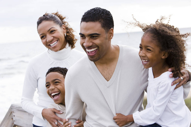 Happy African-American family of four on beach - Photo, image