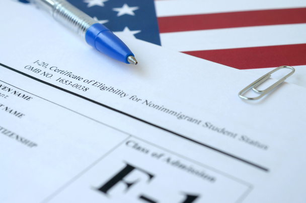I-20 Świadectwo kwalifikowalności do statusu studenta niebędącego imigrantem pusty formularz znajduje się na fladze Stanów Zjednoczonych z niebieskim długopisem z Departamentu Bezpieczeństwa Wewnętrznego - Zdjęcie, obraz