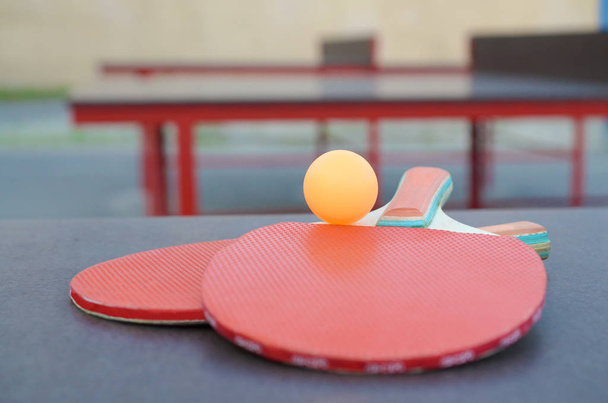 rakety a míč na ping pong stolku ve venkovním sportovním dvoře. Koncept aktivního sportu a tělesné výchovy - Fotografie, Obrázek