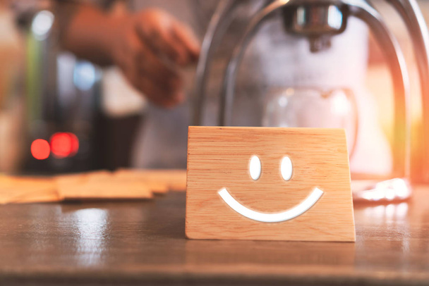 Значок улыбающегося лица на деревянной вывеске. Оптимистичный человек или люди, чувствующие себя внутри и рейтинг обслуживания, концепция удовлетворения
. - Фото, изображение