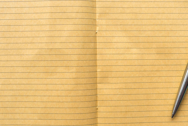 Widok z góry zamknięty żółty notatnik z teksturą linii i długopisem. - Zdjęcie, obraz