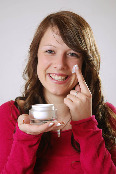 young woman with a jar of cream on her face - 写真・画像