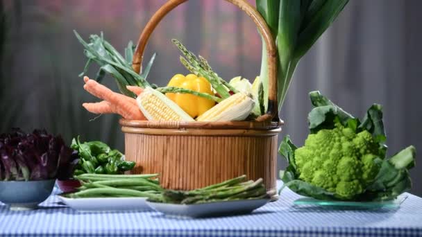 Apreciando uma cesta de deliciosos legumes frescos com aparência cercada por vários pratos com vegetais diferentes em uma mesa com uma toalha de mesa quadriculada. Conceito alimentar saudável e vegan
. - Filmagem, Vídeo