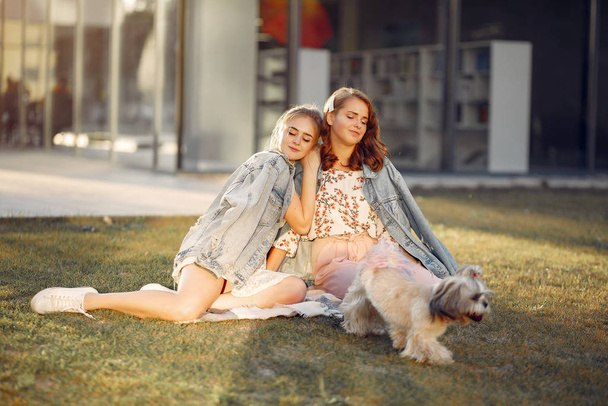 Two girls sitting in a park with a little dog - Фото, зображення