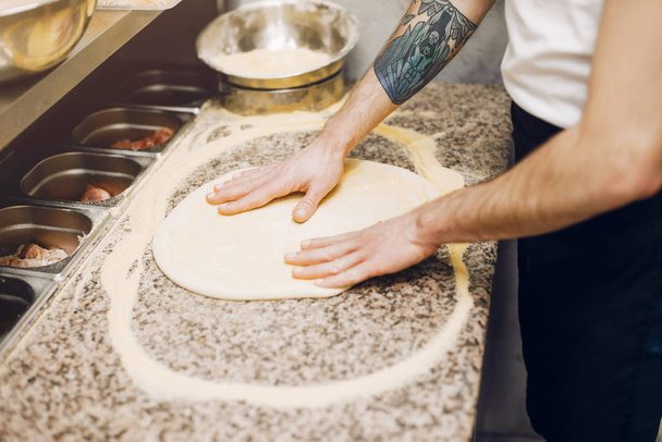Chef in the kitchen prepares pizza - Фото, изображение