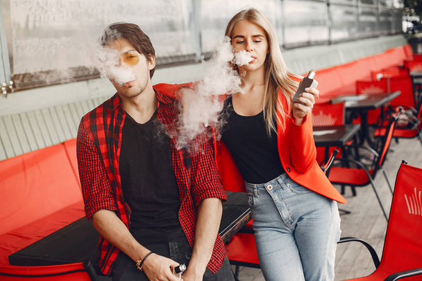 Stylish young couple with vape in a city - Foto, afbeelding