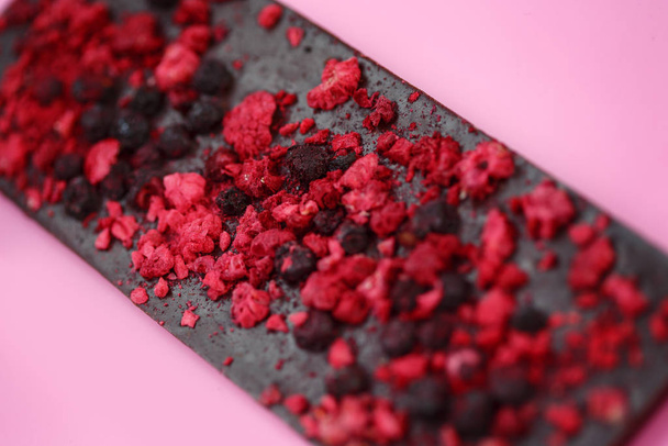 Black low calorie chocolate with dried red berries on bright pink background - Foto, Imagem