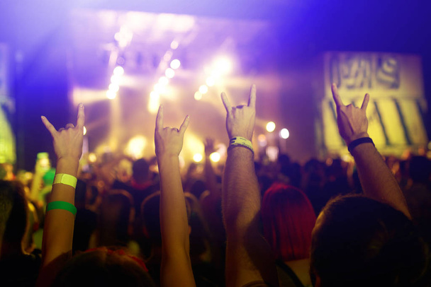 Käsi ja puhelin äänittävät live-musiikkifestivaalia. Ihmiset ottavat valokuvia älypuhelimella julkisen musiikkikonsertin aikana. Yleisö nostaa kätensä, tanssii ja nauttii konsertista.
. - Valokuva, kuva
