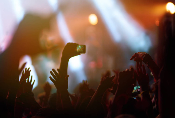 Hand met een telefoon neemt live muziek festival. Mensen die foto 's maken met een smartphone tijdens een publiek muziekconcert. Het publiek steekt zijn hand op, danst en geniet van het concert. - Foto, afbeelding