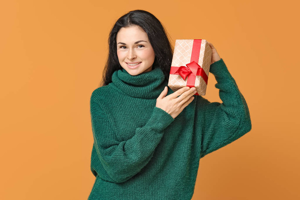 schöne junge Frau mit Geschenk auf farbigem Hintergrund - Foto, Bild
