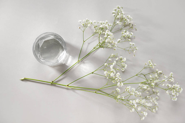 Bicchiere di acqua pulita e fiori su sfondo chiaro
 - Foto, immagini
