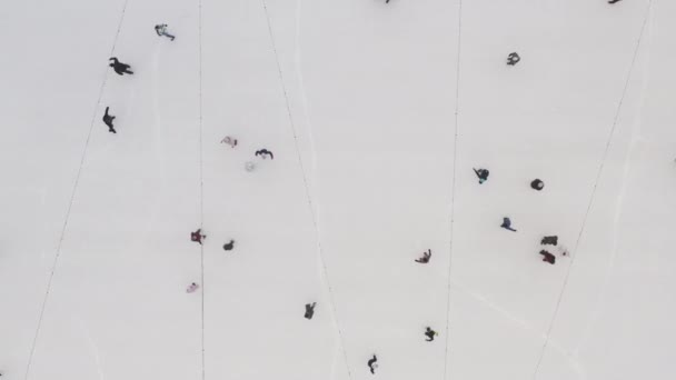 Vista dall'alto di persone che scivolano sul ghiaccio di una pista di pattinaggio all'aria aperta nel centro della città. L'idea di attività sportive per il nuovo anno e il Natale. Persone che pattinano a Kharkov, Ucraina
. - Filmati, video