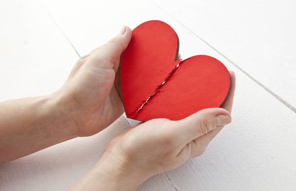 The broken red wooden heart in woman's hands - Fotografie, Obrázek