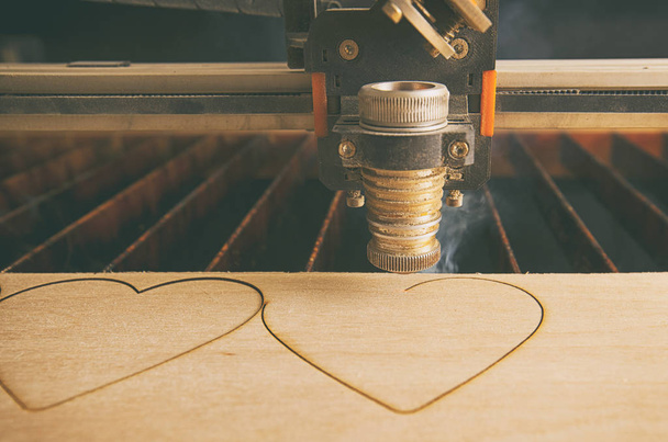 Laser cutting machine is cutting hearts in the wooden plank - Foto, Imagen
