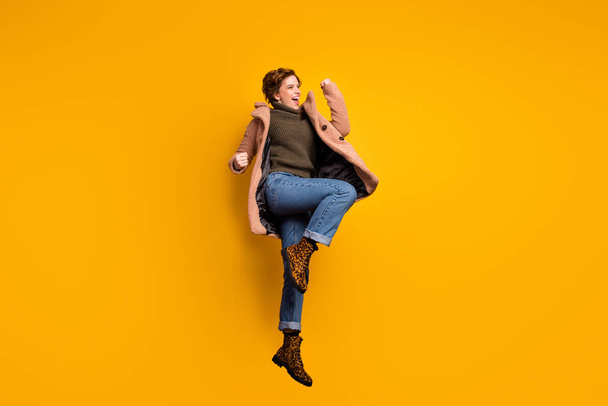 Full size profile photo of funky beautiful lady jump high up astonished vacation start wear casual pink coat pullover jeans leopard footwear isolated yellow color background - Foto, immagini