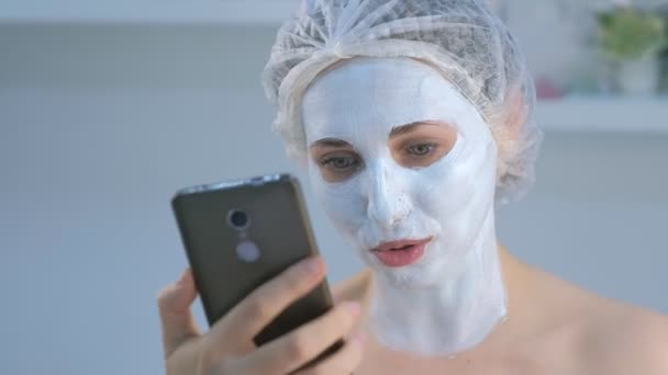 Woman blogger making selfie with facial mask on mobile phone in beauty clinic. - Footage, Video