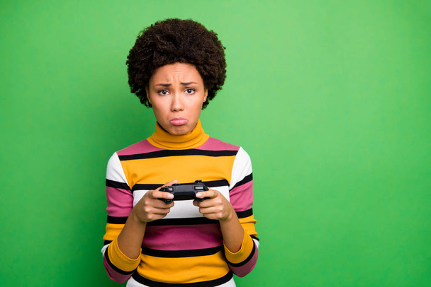Photo of bad mood dark skin wavy lady playing video games joystick hands loser awful player crying sorrow wear casual striped sweater isolated green color background - 写真・画像