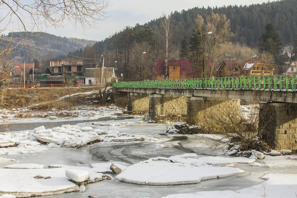 Bridge over frozen river Prut in Carpathian village Yaremche in winter. Ukraine - Photo, Image