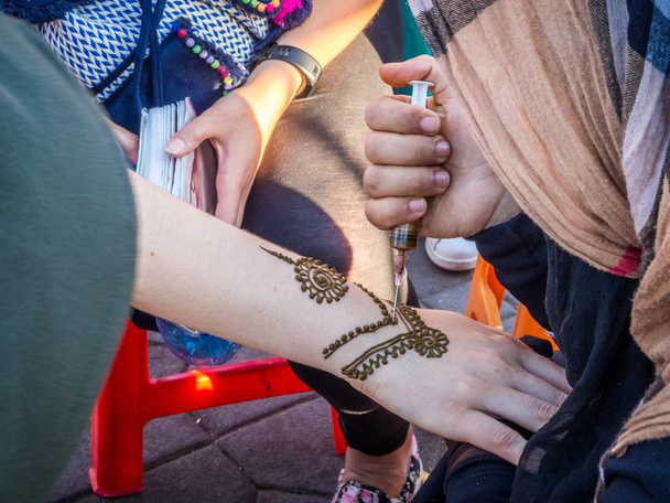 Artist making a traditional henna tattoo on a female's hand in Morocco - Zdjęcie, obraz